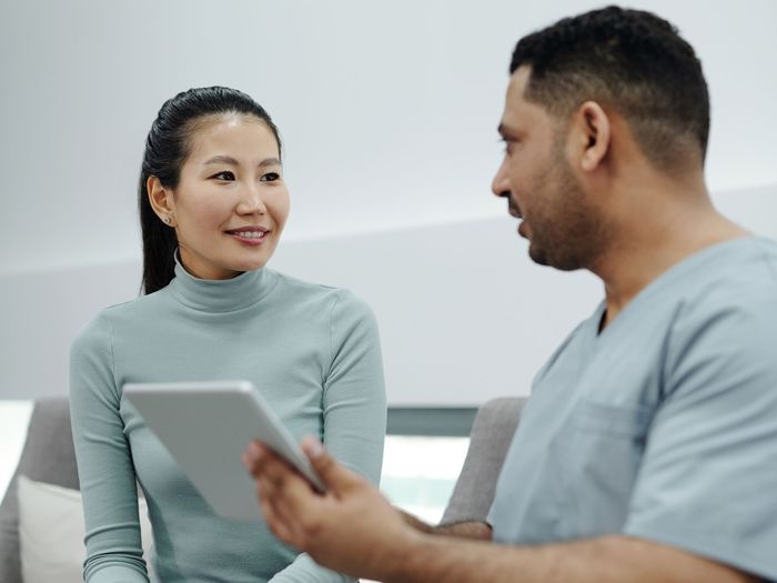 A patient talks with a clinician who is holding a tablet