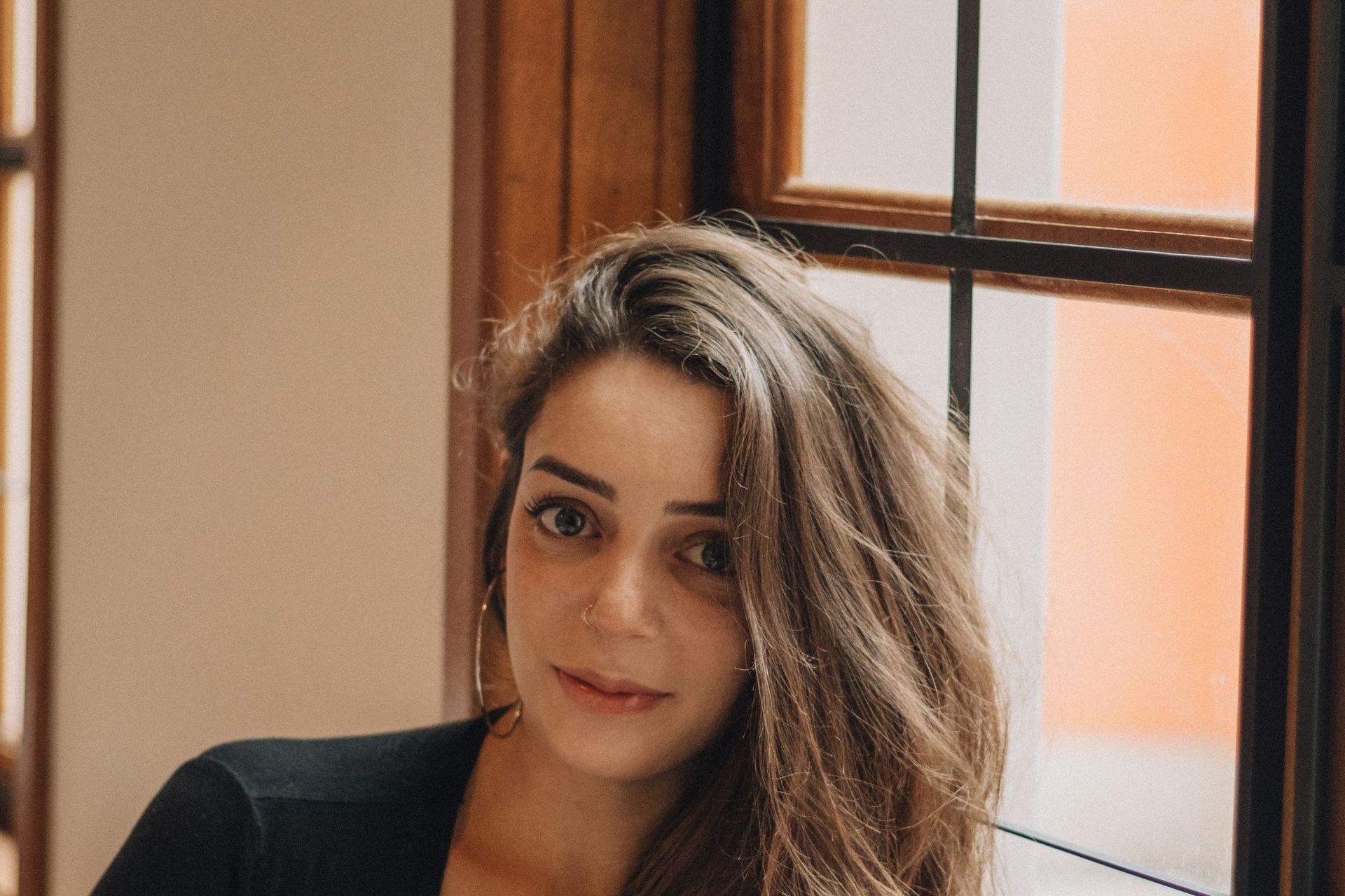 A woman sits by a window in soft natural light